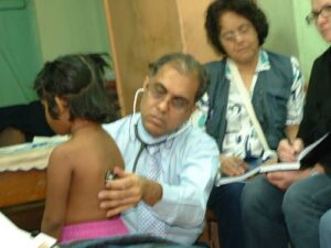 Dr Subrata Banerjea checking up a child to understand her medical condition and students taking notes on the same